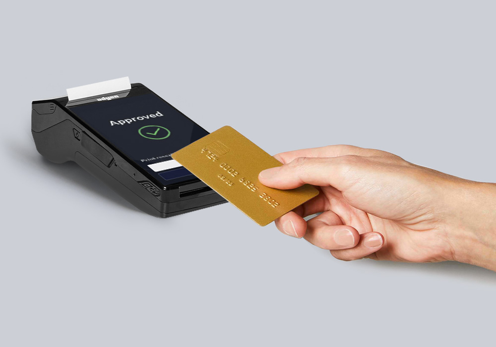 A gold card being tapped on a black payment terminal